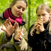 Leiterin erklärt einem Mädchen eine Graspfeife.