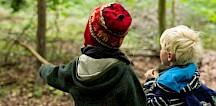 Zwei Kinder im Wald zeigen auf etwas